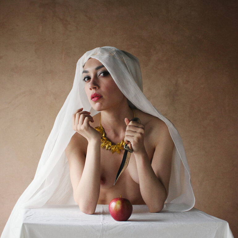 Symbolic fine art nude photograph of a veiled woman holding a dagger and apple, exploring desire, danger, and control.