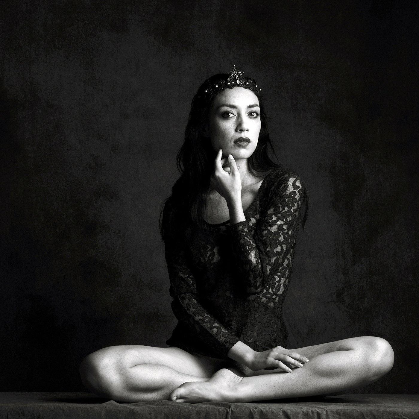 Black and white fine art portrait of a crowned woman seated in a composed pose, conveying authority, stillness, and strength.