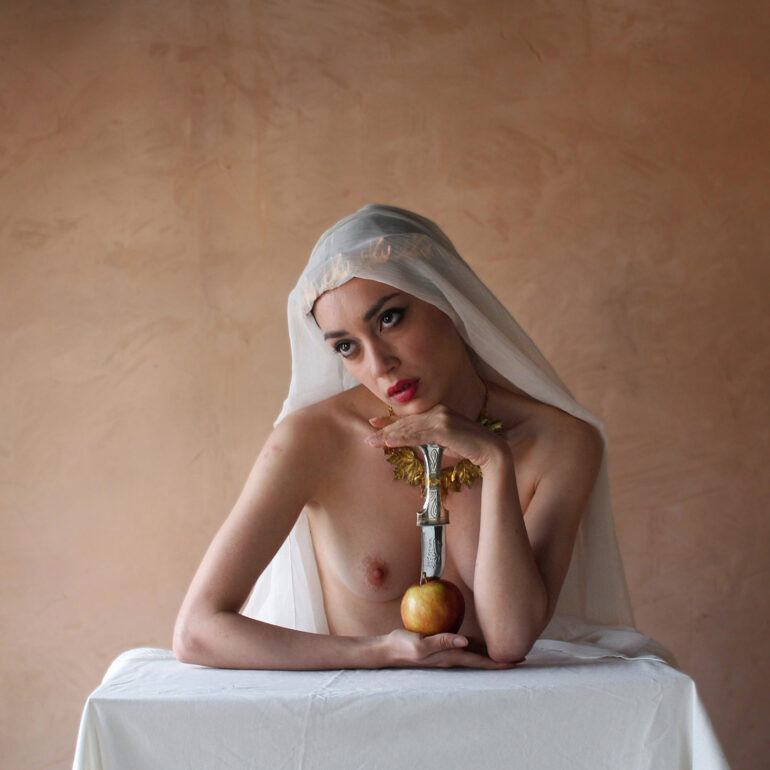 Surreal fine art nude depicting a veiled female figure with an apple and ceremonial dagger, inspired by biblical and mythic symbolism.