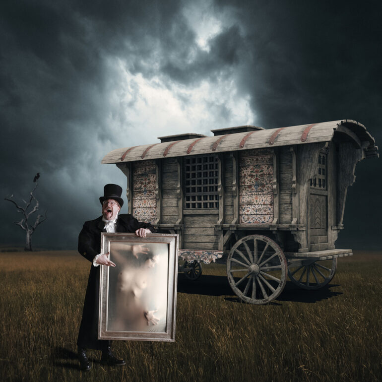 Surreal dark fantasy artwork depicting a Victorian showman holding a framed ethereal nude figure before a mysterious caravan under stormy skies, evoking gothic horror, illusion, and theatrical spectacle.